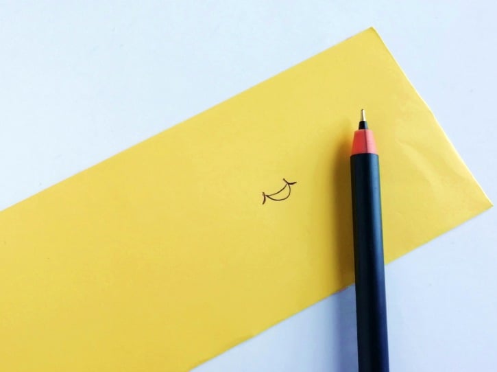 smile drawn on yellow paper with pen